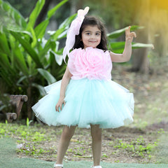 A young girl wearing a pink and white floral dress with a tutu skirt, standing in a garden setting.