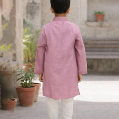 Child wearing a pink kurta with white pants standing in an outdoor setting.