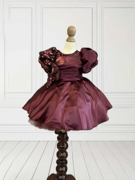 This wine coloured beautiful kids frock with a back zip closure has sequin and pleated detailing on its yoke that adds grace to the look. It features cute bow detailing on the waist curated from sequin fabric. Moreover, it comes with a fabric belt to be tied at the back.