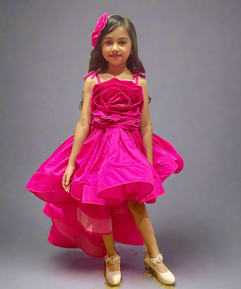 It is a designer neon pink colored up-and-down birthday girl dress that comes with a back hook closure and has a big floral detailing in the dress.