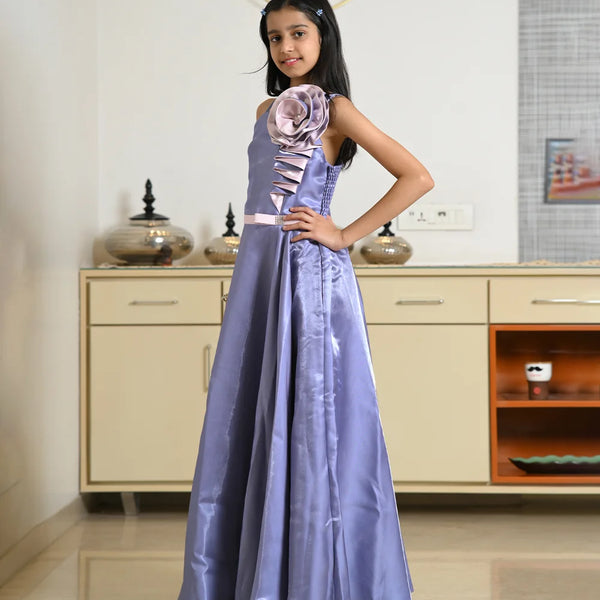 Young girl in a long purple dress with floral details standing in a room.