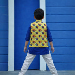 Child wearing a colorful vest with elephant patterns against a blue wall.