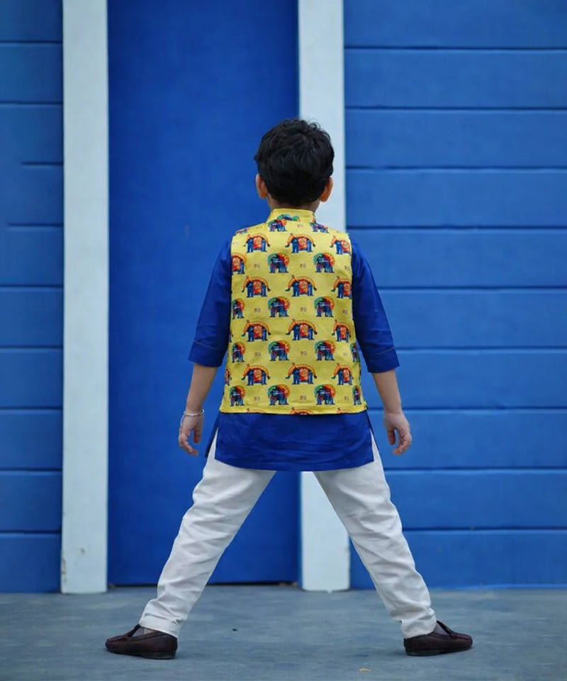 Child wearing a colorful vest with elephant patterns against a blue wall.