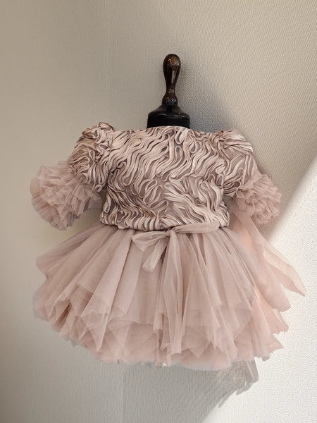 Pink dress with ruffled top and layered skirt on a mannequin against a neutral background