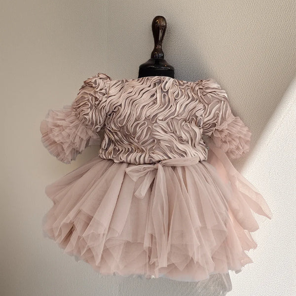 Pink dress with ruffled top and layered skirt on a mannequin against a neutral background