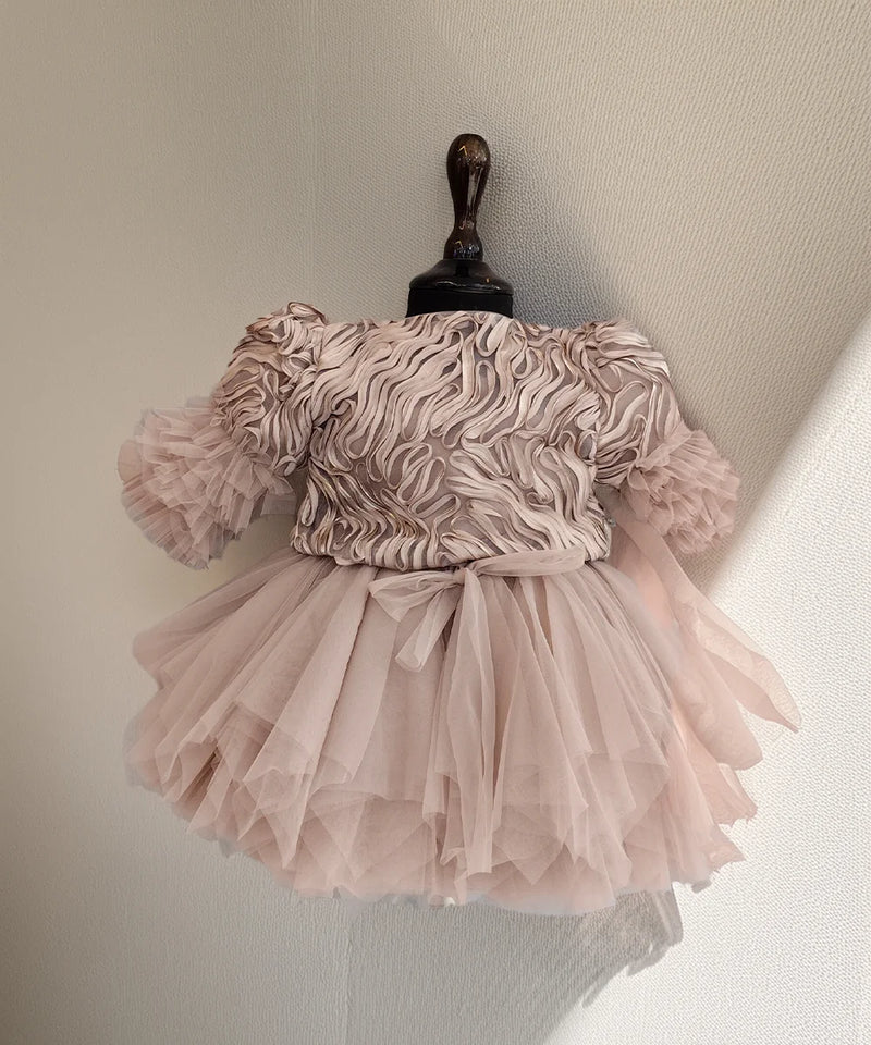 Pink dress with ruffled top and layered skirt on a mannequin against a neutral background