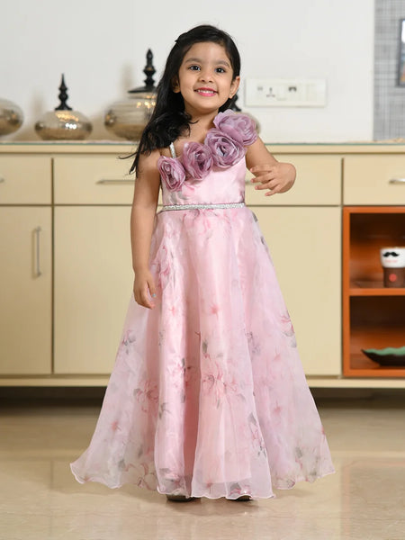 Young girl in a pink floral dress standing in a room with cabinets.
