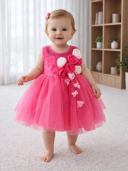 Baby in a pink dress with floral decorations standing in a room.