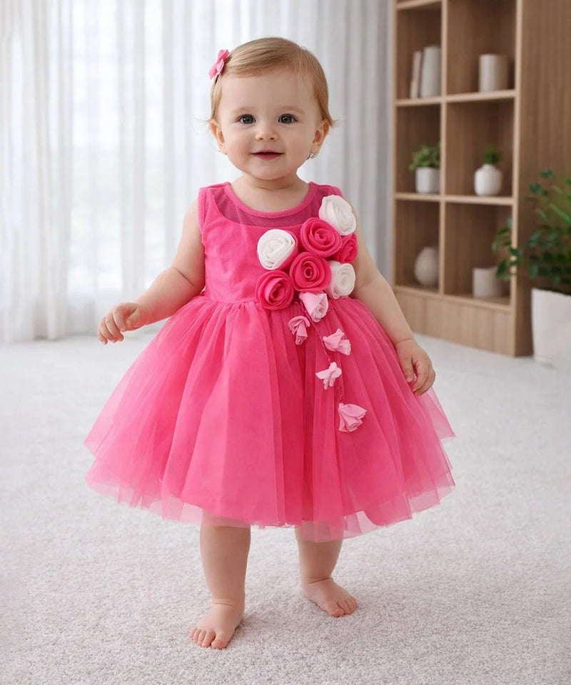 Baby in a pink dress with floral decorations standing in a room.