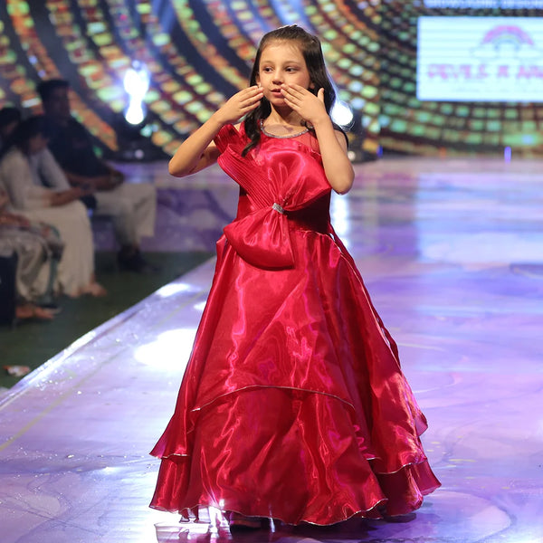 Baby girl in a red gown on a stage with a colorful background