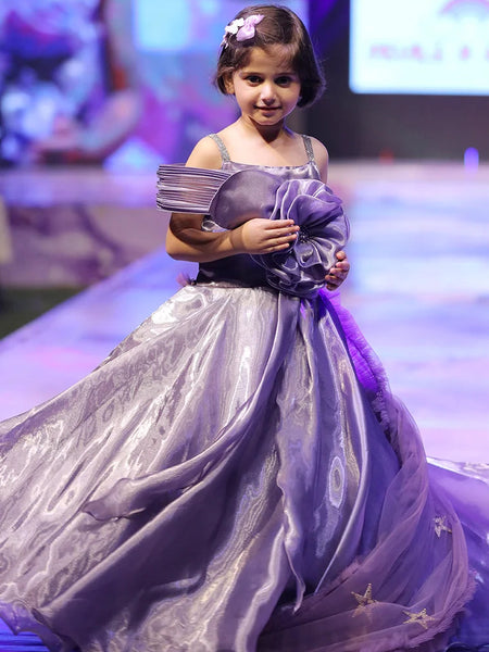 Young girl in a purple dress on a runway at a fashion event.