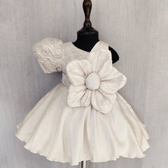 White dress with a large floral embellishment on a mannequin against a light gray background