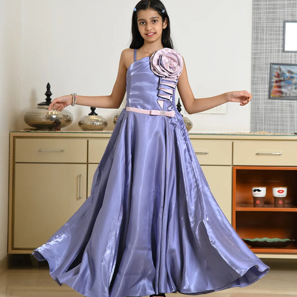 Young girl in a purple gown with floral details standing indoors.