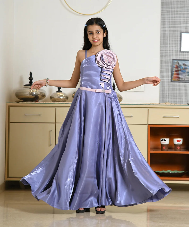 Young girl in a purple gown with floral details standing indoors.