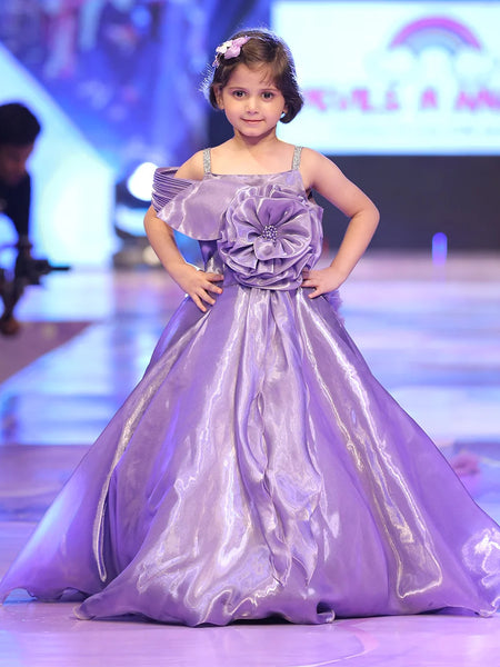 Young girl in a purple dress on a runway at a fashion show.