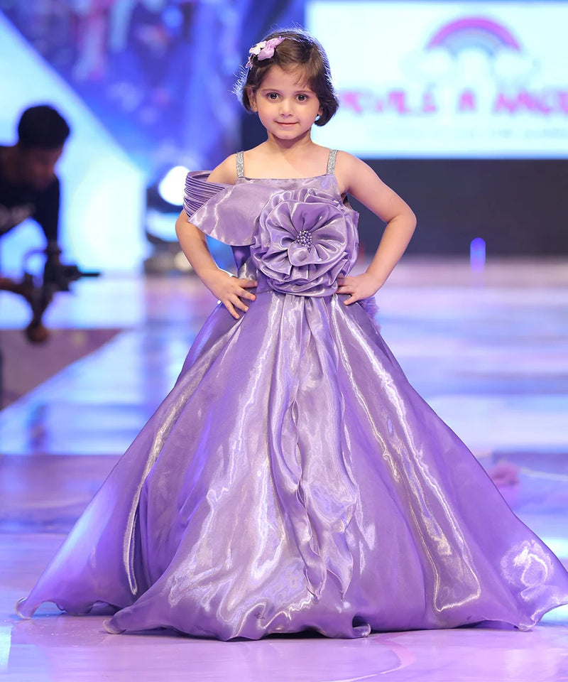 Young girl in a purple dress on a runway at a fashion show.