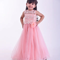 Young girl wearing a pink dress with floral details on a white background