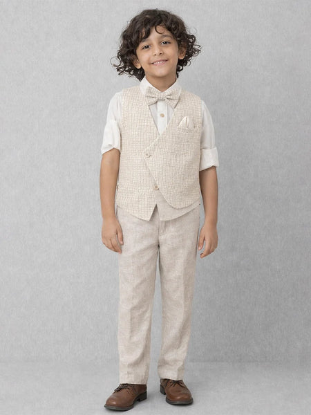 Young boy wearing a beige vest and pants set on a gray background