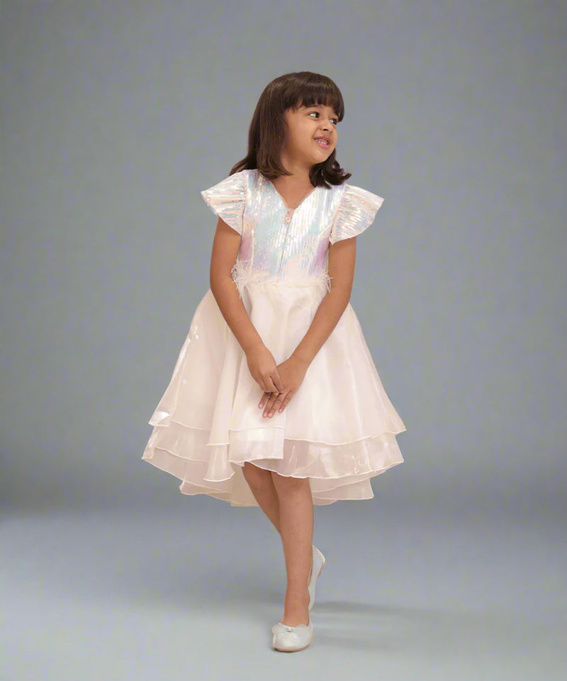 It's a cute white coloured up-and-down birthday frock with a back zip closure. A perfect marriage wears for girls. It features a bow on the back and beautiful feather detailing on the waist that uplifts the entire look.