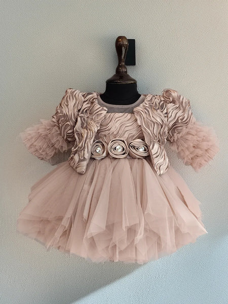 Pink dress with floral embellishments on a mannequin against a light blue background