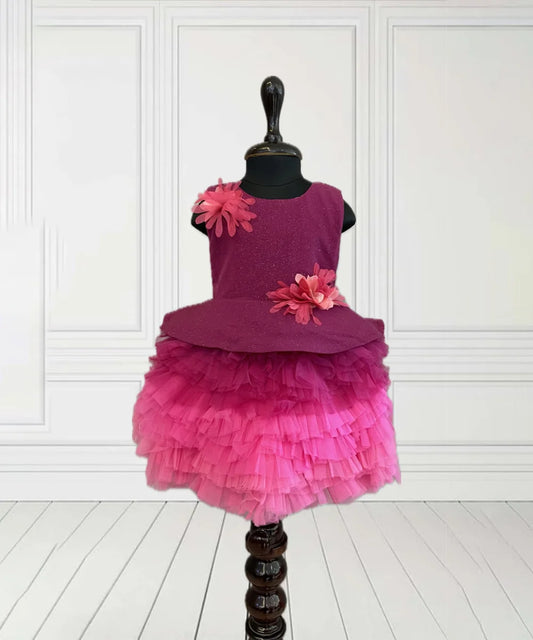  It’s a rani pink coloured frill frock that comes with a back zip closure. It’s a trendy dress for kids. It features floral detailing on the shoulder and the waist that adds grace to the look. 