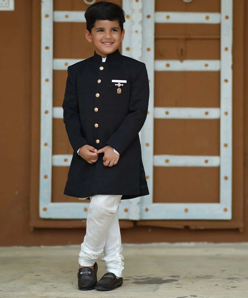 This full-sleeve self-textured black achkan with stand collar neck and designer broach comes with a white kurta-pyjama that gives this set an elegant look.