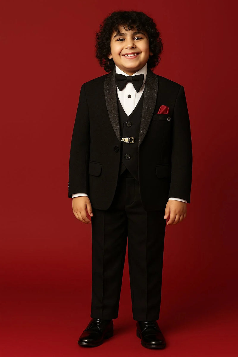 Young boy in a formal black suit with a bow tie on a red background