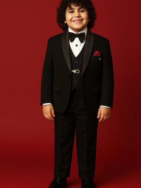 Young boy in a formal black suit with a bow tie on a red background