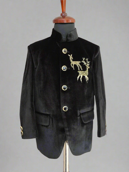 Black velvet suit jacket with gold deer emblem on a mannequin against a beige background