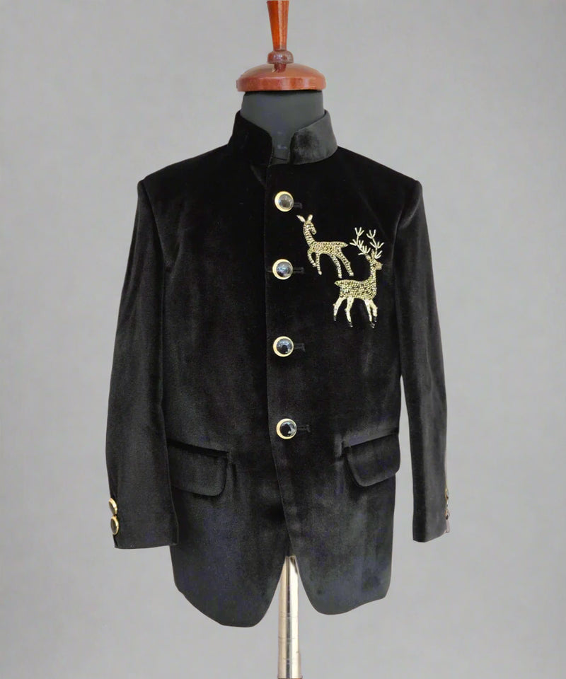 Black velvet suit jacket with gold deer emblem on a mannequin against a beige background