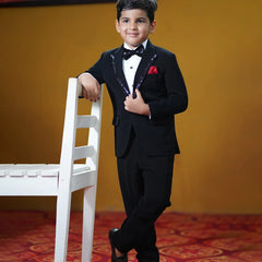 This classic tuxedo is rendered in black color and comes with matching pants, a white shirt, a black bow and a red pocket square. It features a beautiful sequin detailing on the collar and a bow curated from a black sequin fabric.
