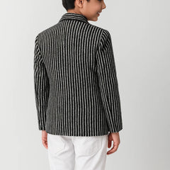 Child wearing a black and white striped shirt with a collar on a plain background