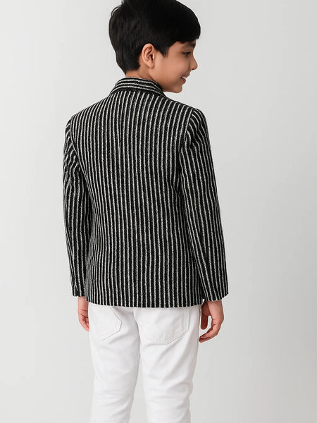 Child wearing a black and white striped shirt with a collar on a plain background