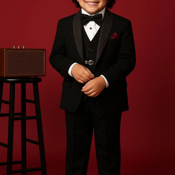 Child in a formal black suit standing against a red background