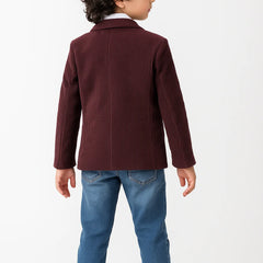 Child wearing a burgundy jacket and blue jeans on a white background