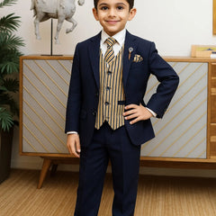 Young boy in a formal suit standing in a room with decorative elements.