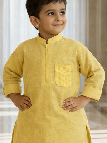 Child wearing a yellow kurta with a plain background