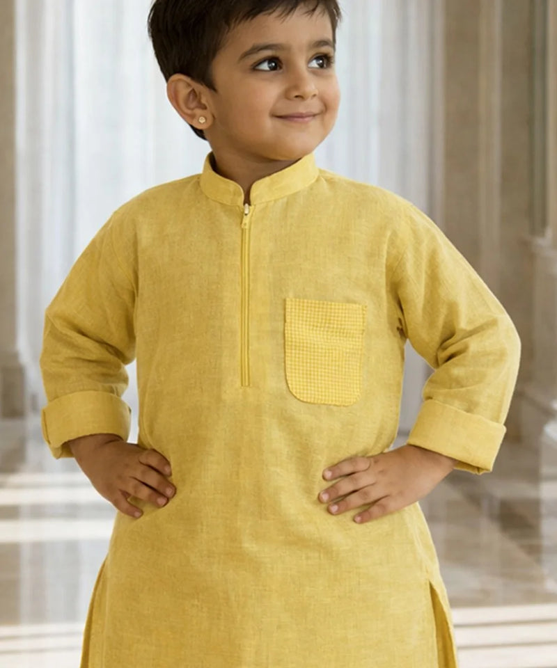 Child wearing a yellow kurta with a plain background