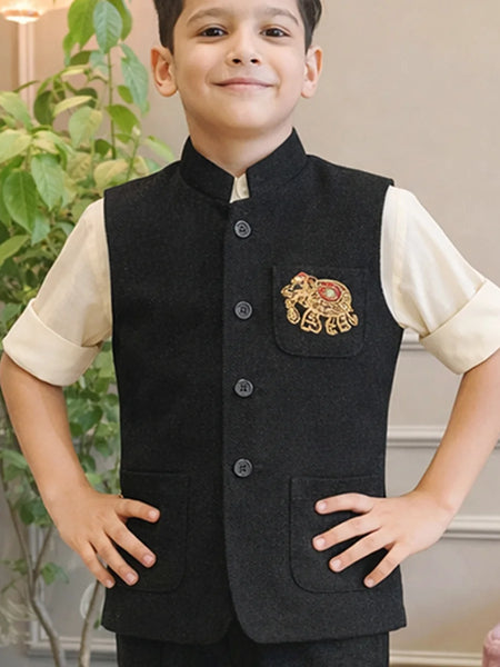 Child wearing a black embroidered vest over a cream shirt with a plant in the background
