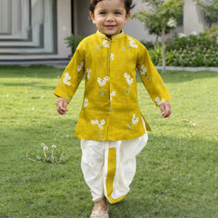 Child wearing a yellow kurta with white floral patterns on a grassy lawn.