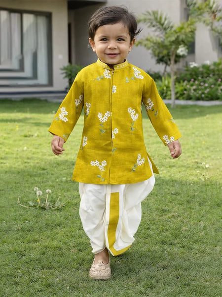 Child wearing a yellow kurta with white floral patterns on a grassy lawn.