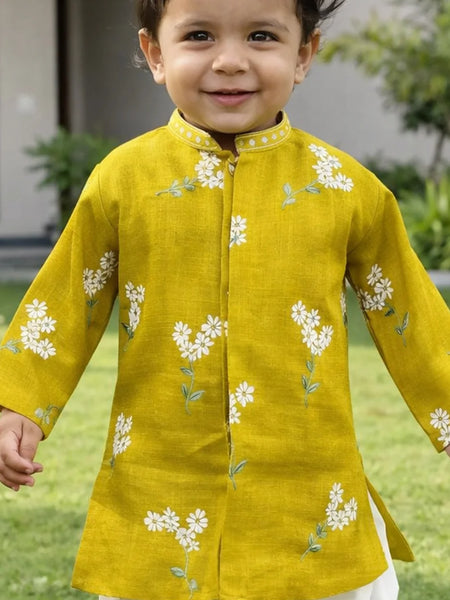 Child wearing a yellow kurta with white floral embroidery outdoors.