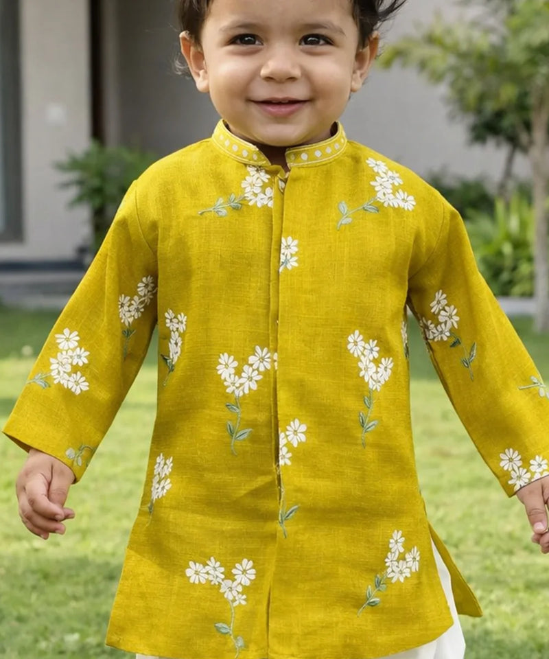 Child wearing a yellow kurta with white floral embroidery outdoors.