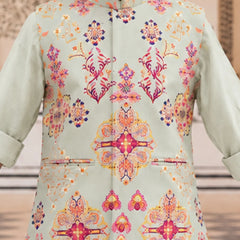 A close-up of a person wearing a light sage green traditional jacket with a vibrant, multicolored floral and geometric pattern in pink, orange, yellow, and blue.