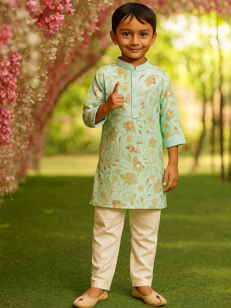 Child in a floral kurta and white pants standing under pink flowers