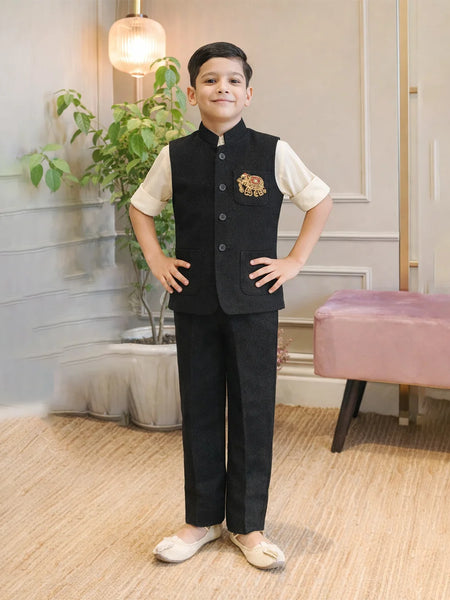 Child wearing a formal outfit with a vest and pants in a room with plants and a pink chair.