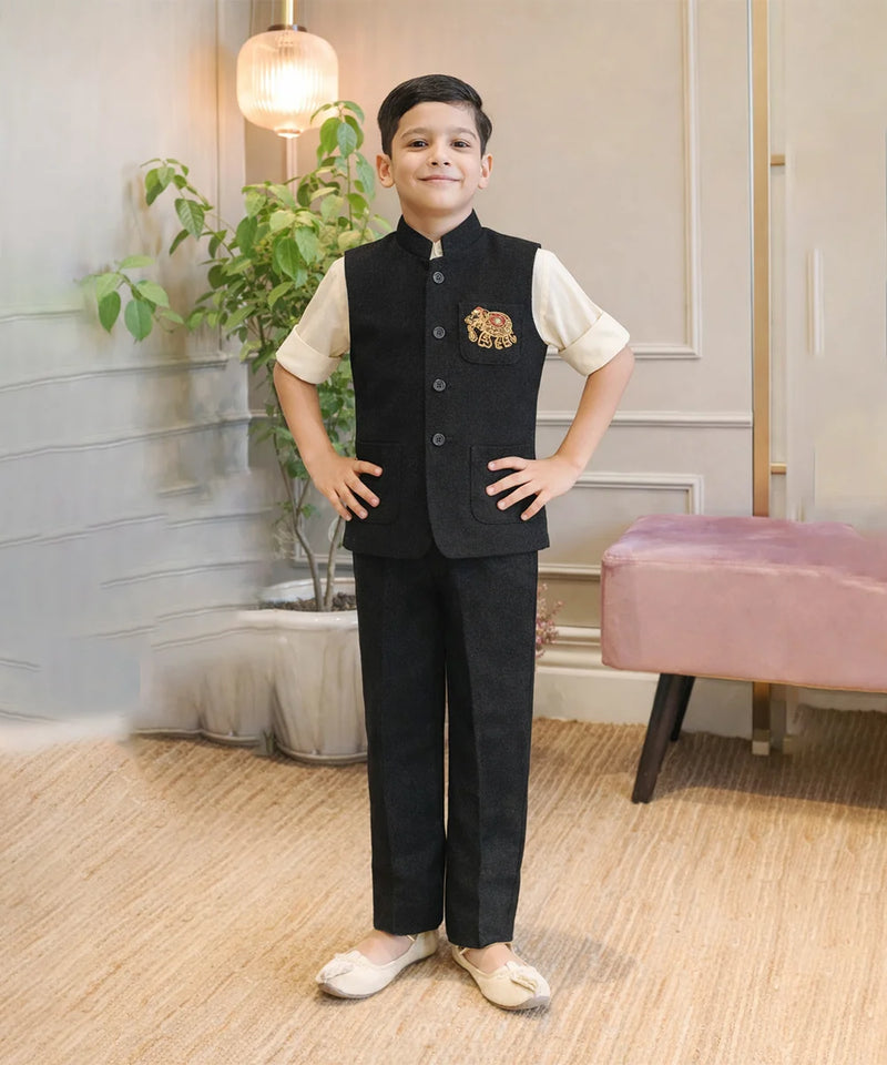 Child wearing a formal outfit with a vest and pants in a room with plants and a pink chair.