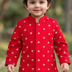 Child wearing a red outfit with heart patterns outdoors