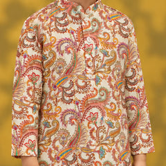 A child wearing a cream-colored kurta with an intricate multicolor paisley pattern in orange, pink, yellow, and green, set against a soft yellow background.