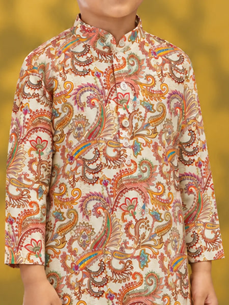 A child wearing a cream-colored kurta with an intricate multicolor paisley pattern in orange, pink, yellow, and green, set against a soft yellow background.